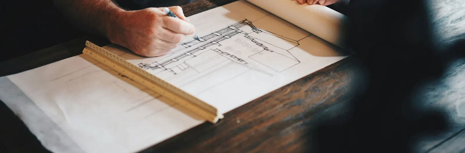 Architect drawing a house plan by hand with a pencil and scale ruler